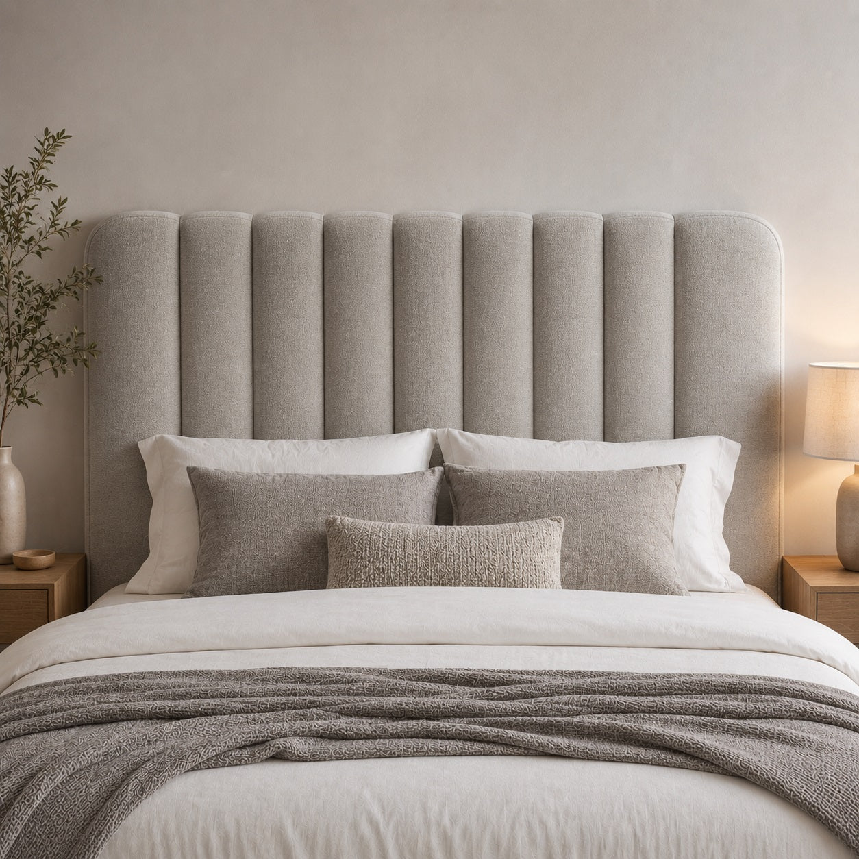 Tête de lit en tissu rembourrée avec panneaux verticaux dans une chambre moderne et apaisante.
