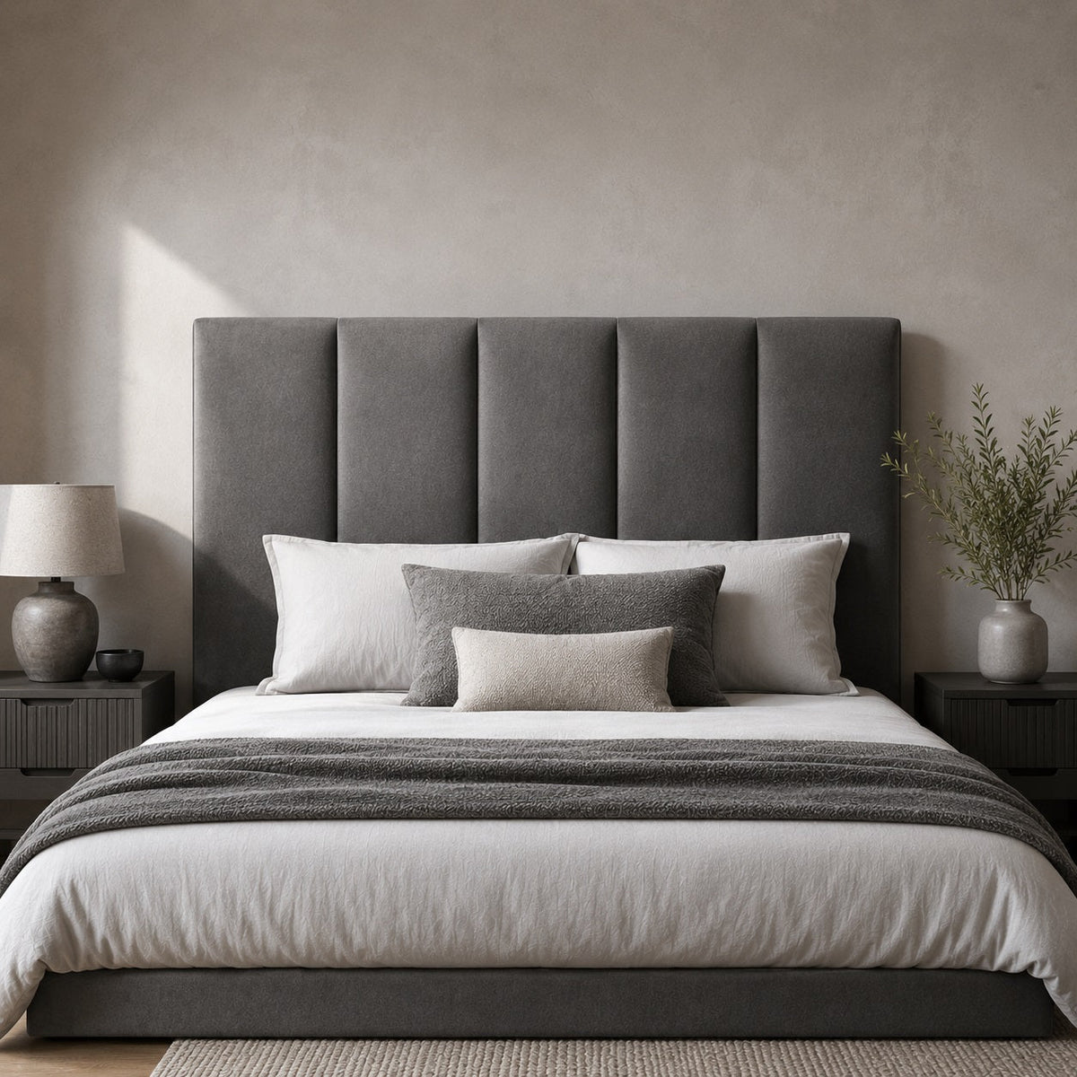 Tête de lit grise rembourrée avec panneaux verticaux dans une chambre au style moderne et élégant.