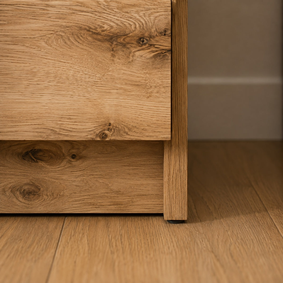 Détail de la base de la commode en bois 5 tiroirs avec finition chêne et lignes minimalistes.