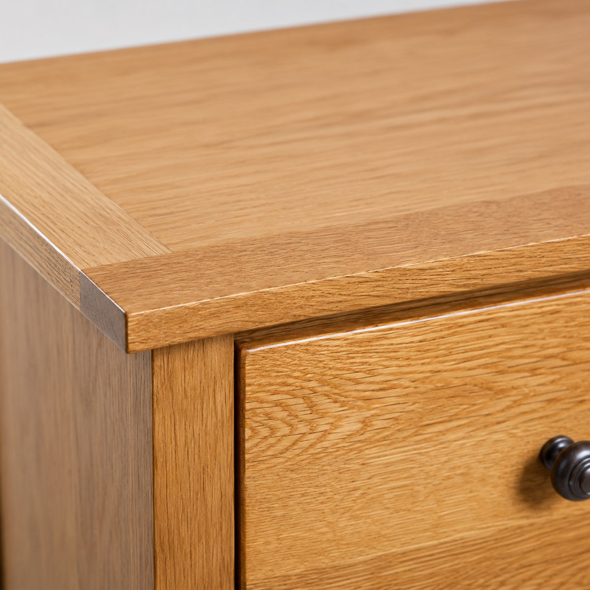 Gros plan sur la finition de la commode en bois, avec veinage naturel, plateau travaillé et poignée ronde.