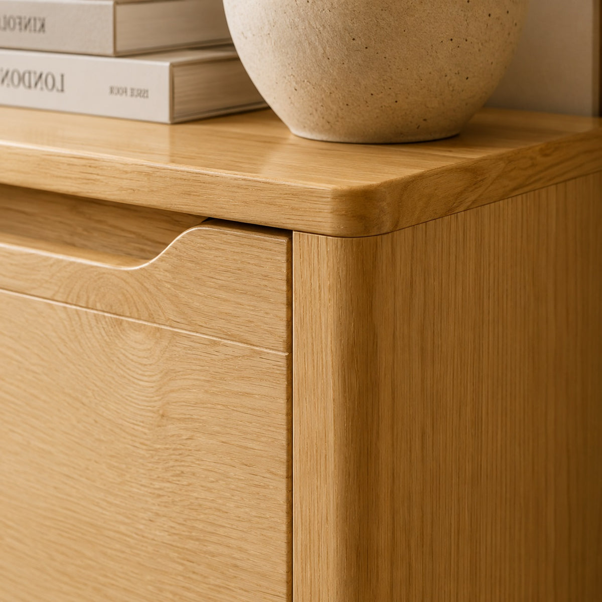 Détail de la commode en bois Maren, finition bois clair, plateau arrondi et poignée intégrée.