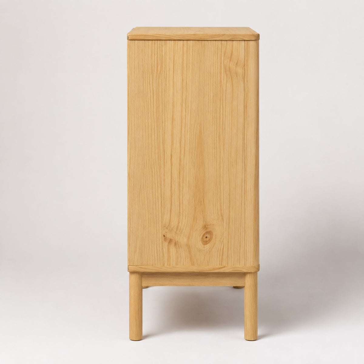 Vue de côté de la commode en bois Maren à 4 tiroirs, finition bois clair et pieds surélevés.