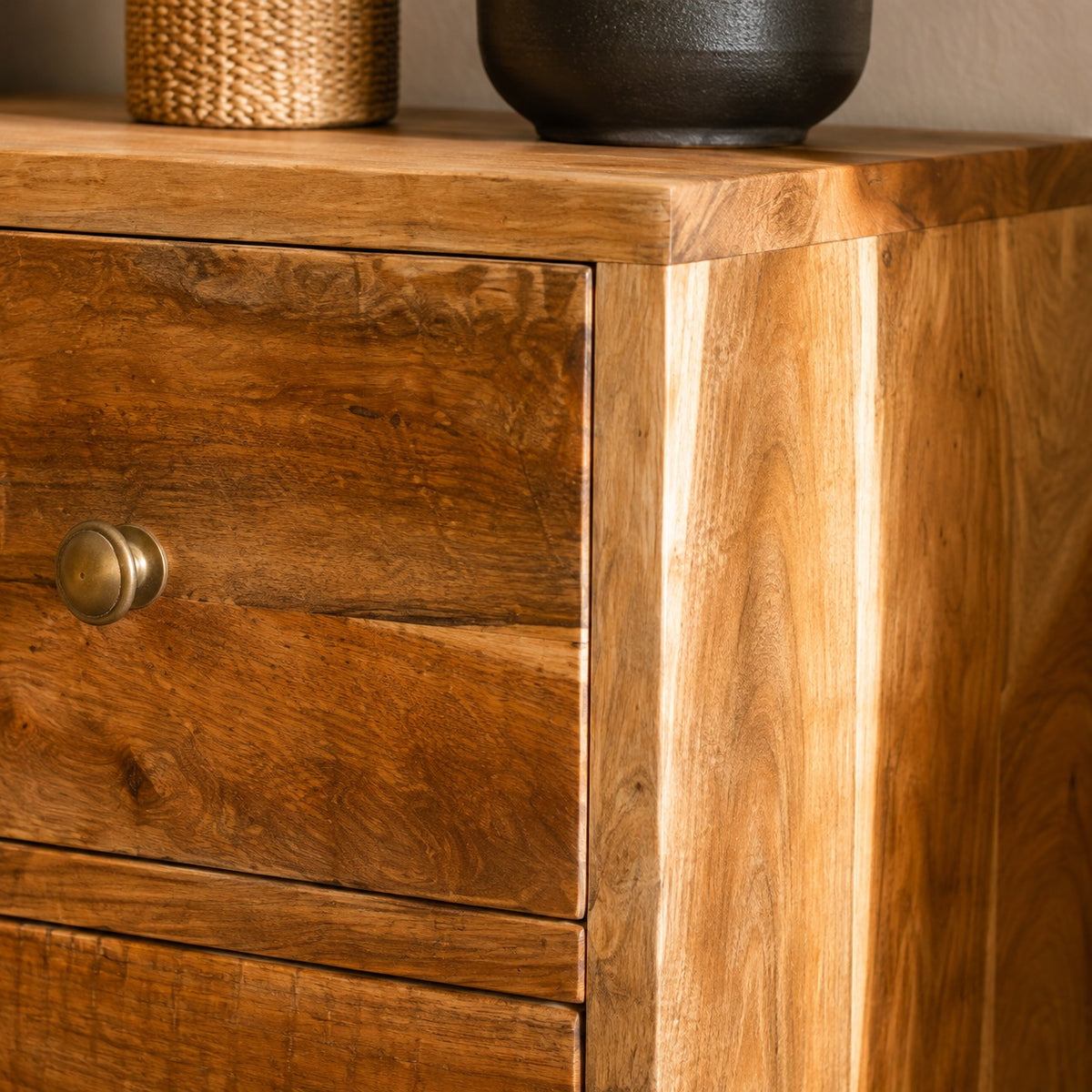 Détail de la commode en bois 5 tiroirs mettant en valeur le veinage naturel du bois et les boutons métalliques.