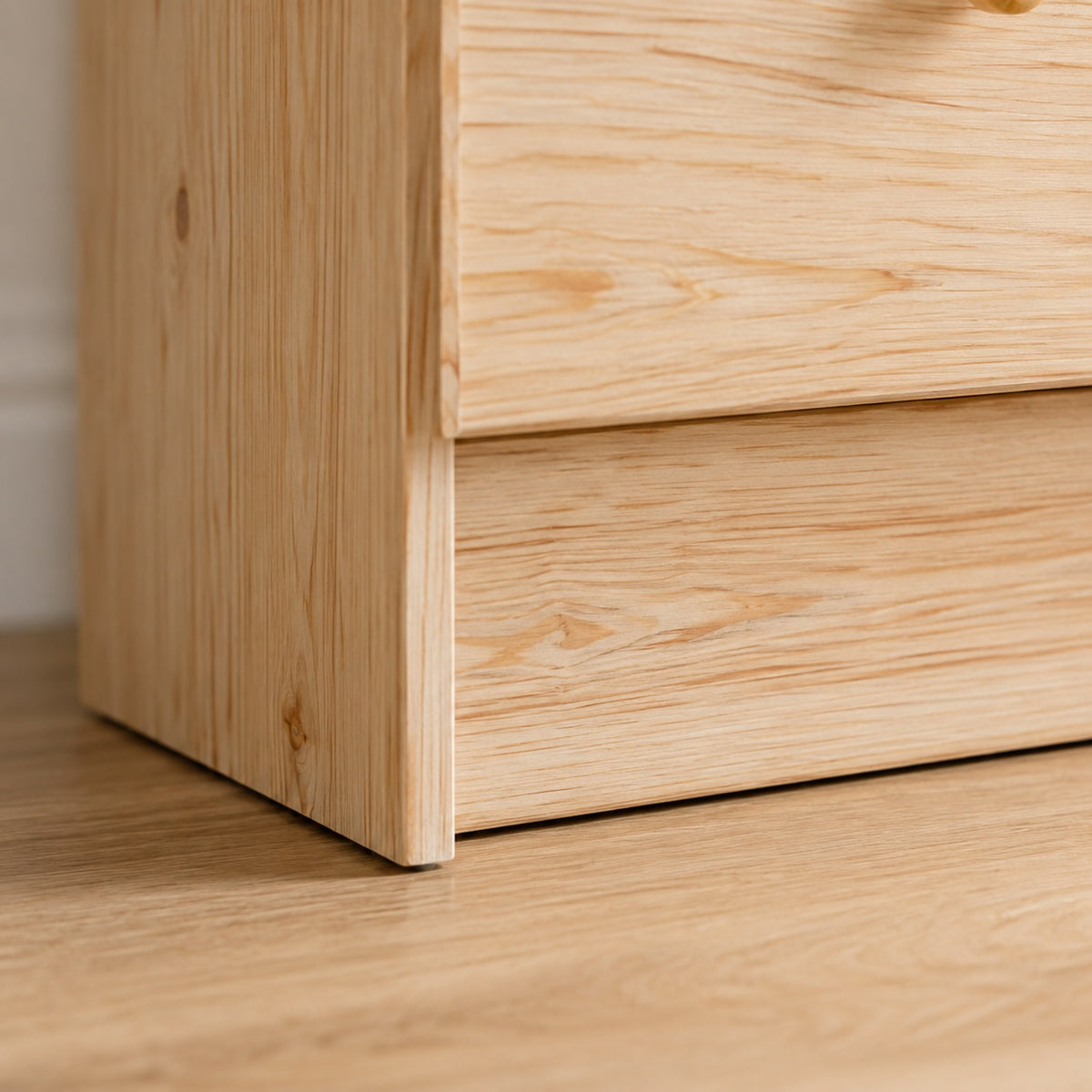 Détail de la base de la commode en bois 7 tiroirs avec finition soignée et bois naturel.