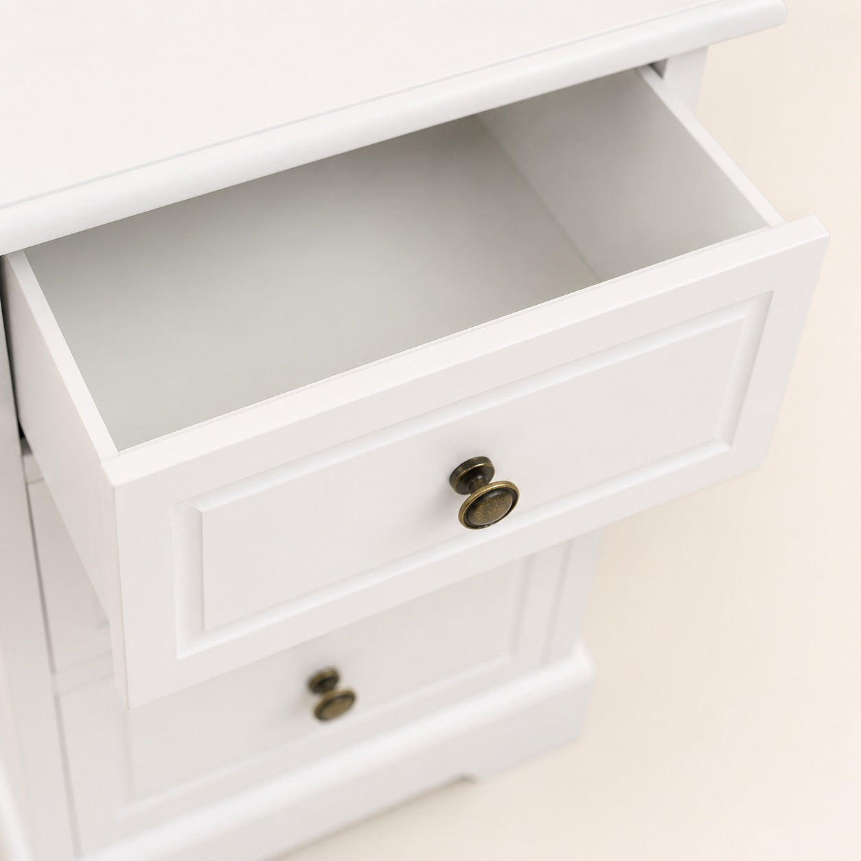 Gros plan sur le tiroir d'une table de chevet vintage blanche avec poignée en métal.