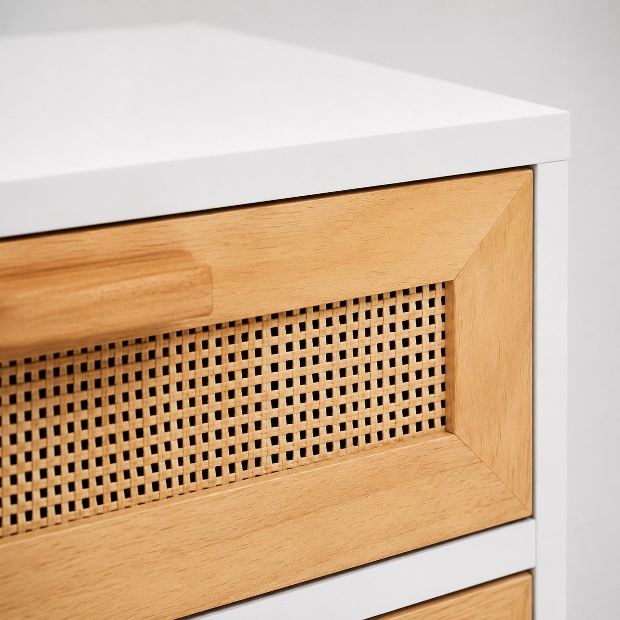 Gros plan sur le cannage et les finitions en bois de cette table de chevet blanche avec cannage.