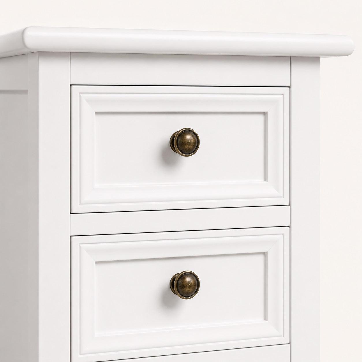 Zoom sur les finitions d'une table de chevet blanche vintage avec poignées en métal vieilli.