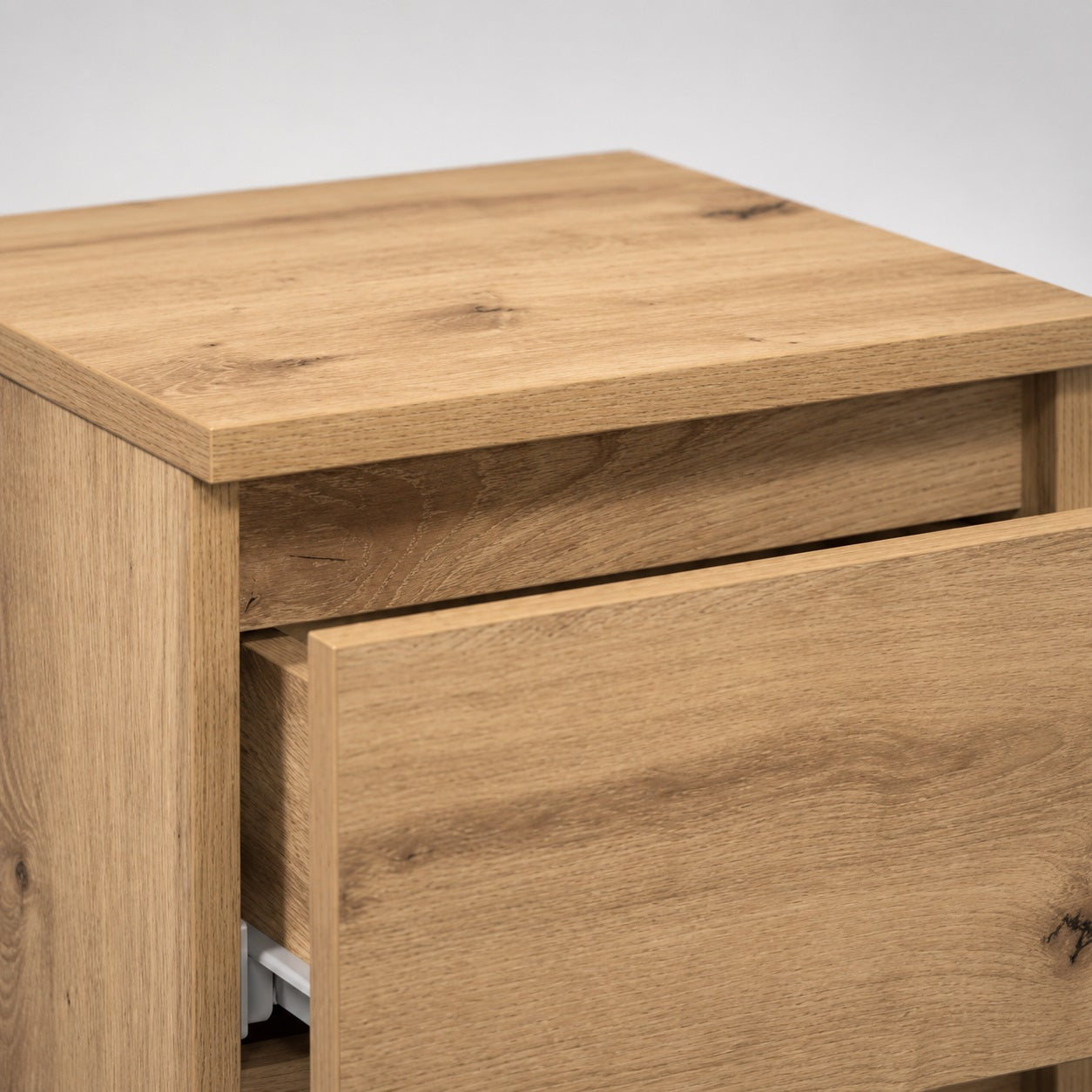 Gros plan sur une table de nuit, table de chevet en bois avec tiroir sur glissières métalliques.