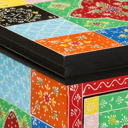 Zoom sur le plateau d'une table de chevet design en bois avec motifs colorés et finition artisanale peinte.