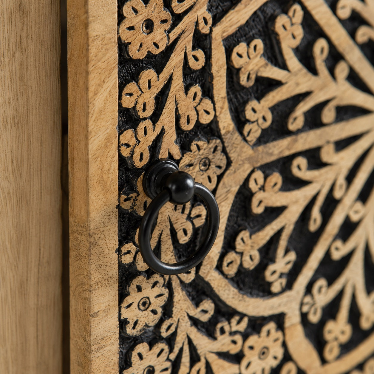 Détail de la façade sculptée et de la poignée de cette table de chevet en bois design.