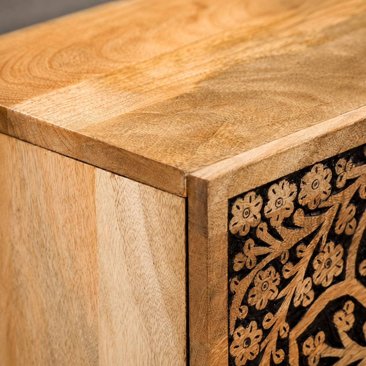 Gros plan sur les finitions de cette table de chevet en bois design avec façade sculptée et veinage naturel du bois.