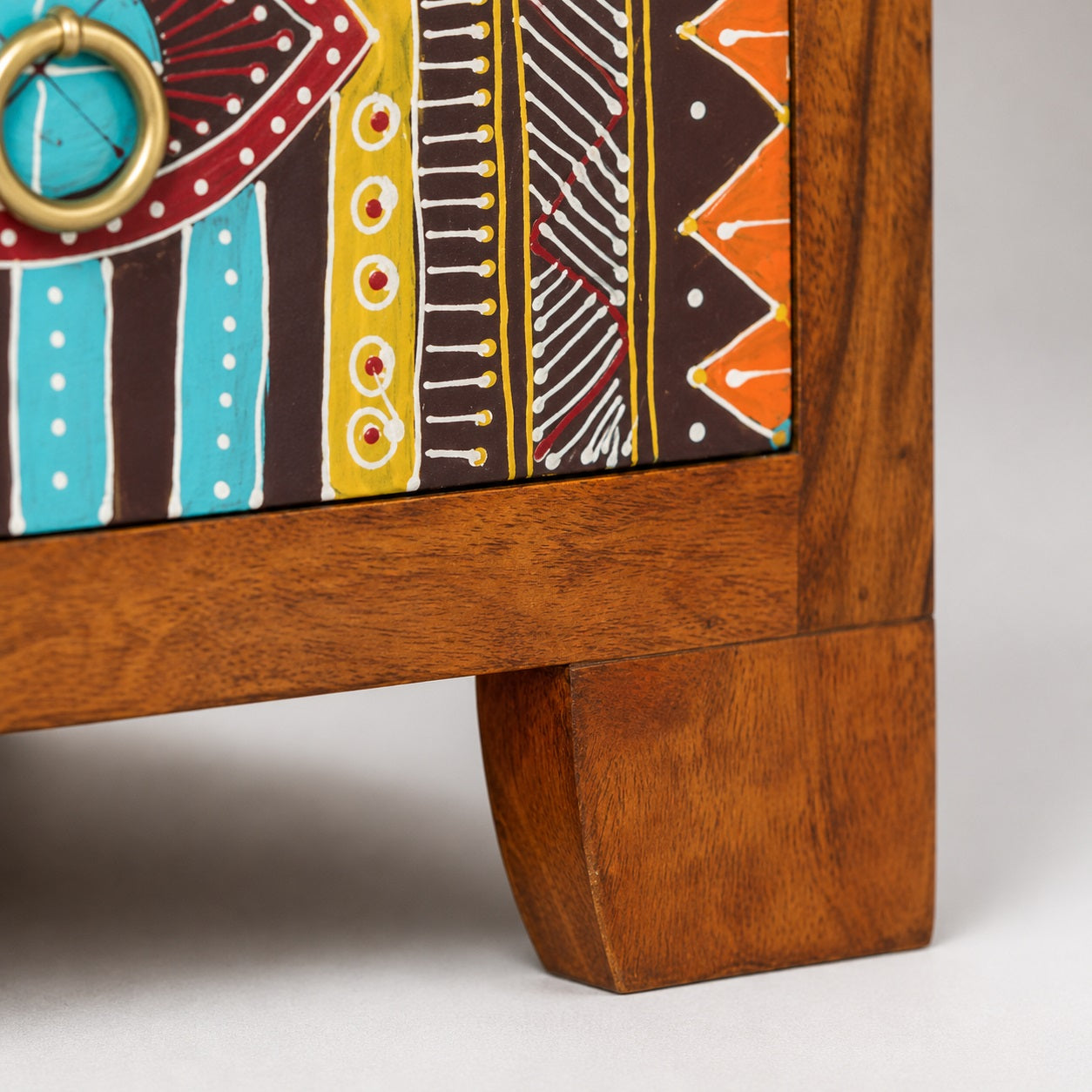 Détail d'une table de chevet design en bois avec façades peintes à la main et poignées en métal.