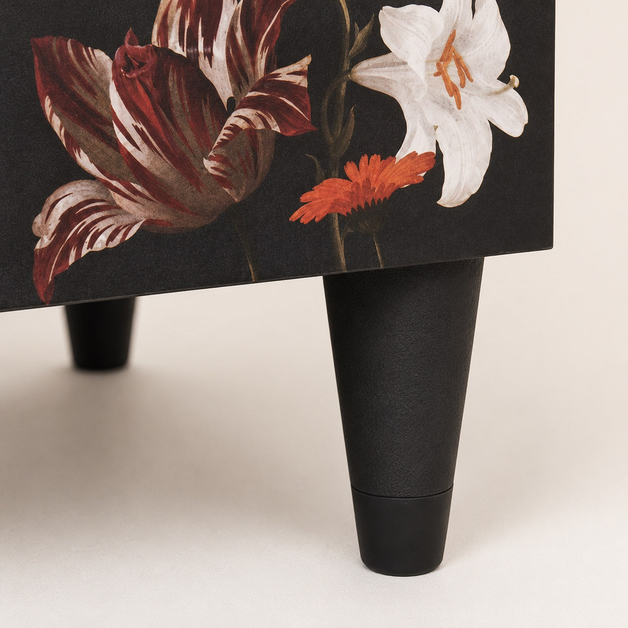 Gros plan sur le pied d'une table de chevet noire design au style moderne et finitions soignées.
