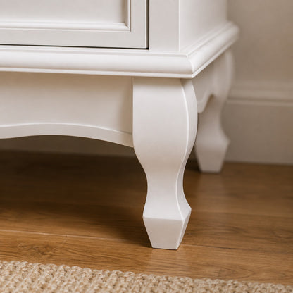 Détail du pied galbé d’une commode blanche vintage, aux finitions classiques et élégantes.