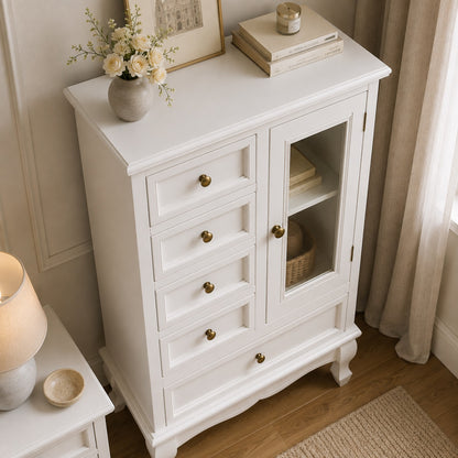 Commode blanche vintage vue en plongée, avec tiroirs, porte vitrée et élégantes poignées dorées.