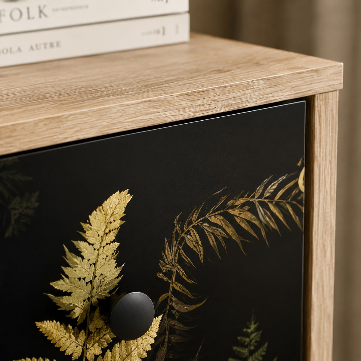 Détail de la commode design Celia avec plateau effet bois clair, motifs végétaux et poignée ronde noire.