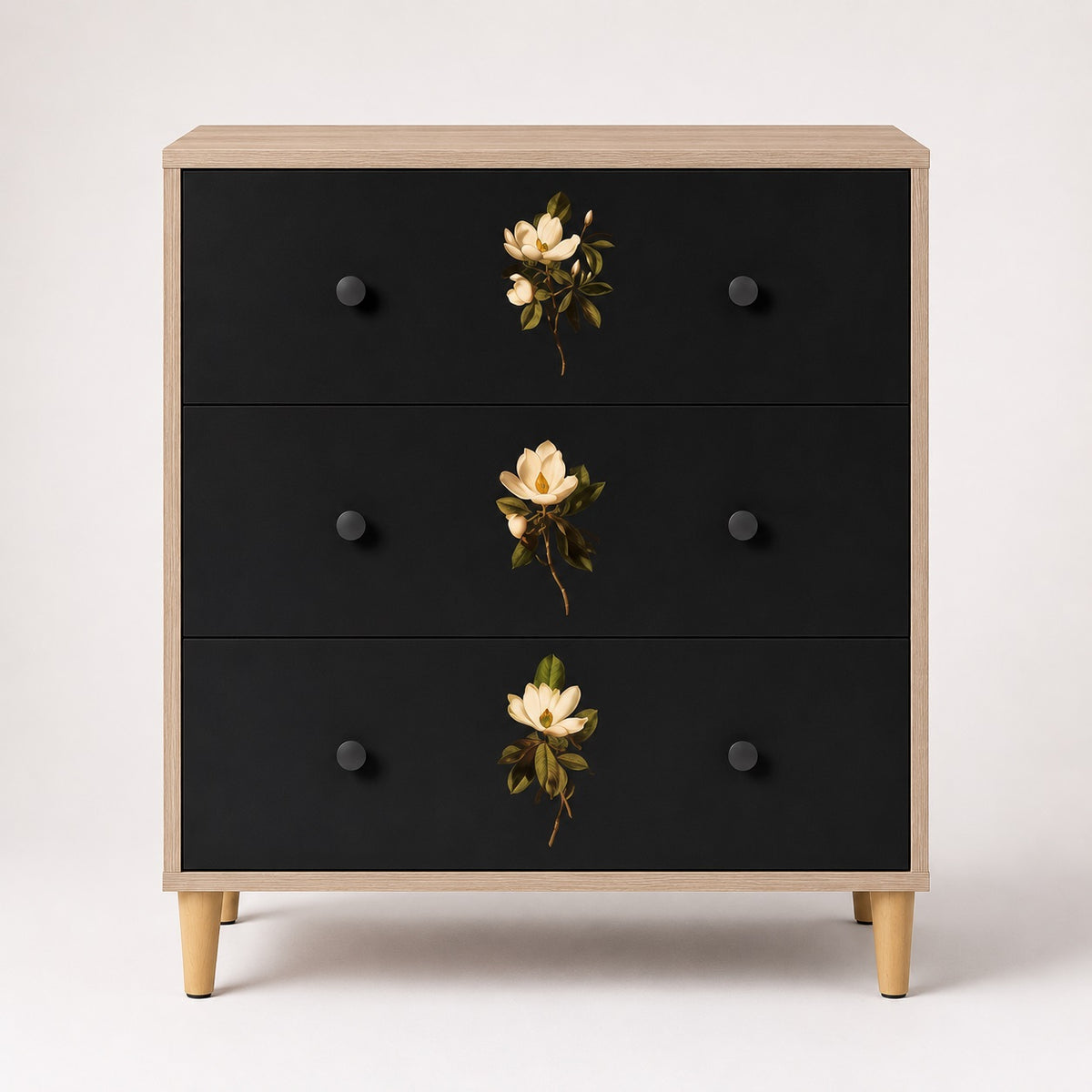 Commode 3 tiroirs Celia vue de face, commode design noire et bois clair ornée de délicats motifs floraux.