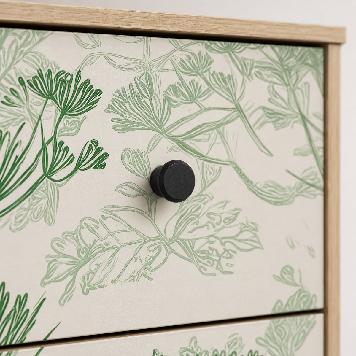 Zoom sur la commode design Dalia, ses motifs floraux verts et ses poignées rondes noires.