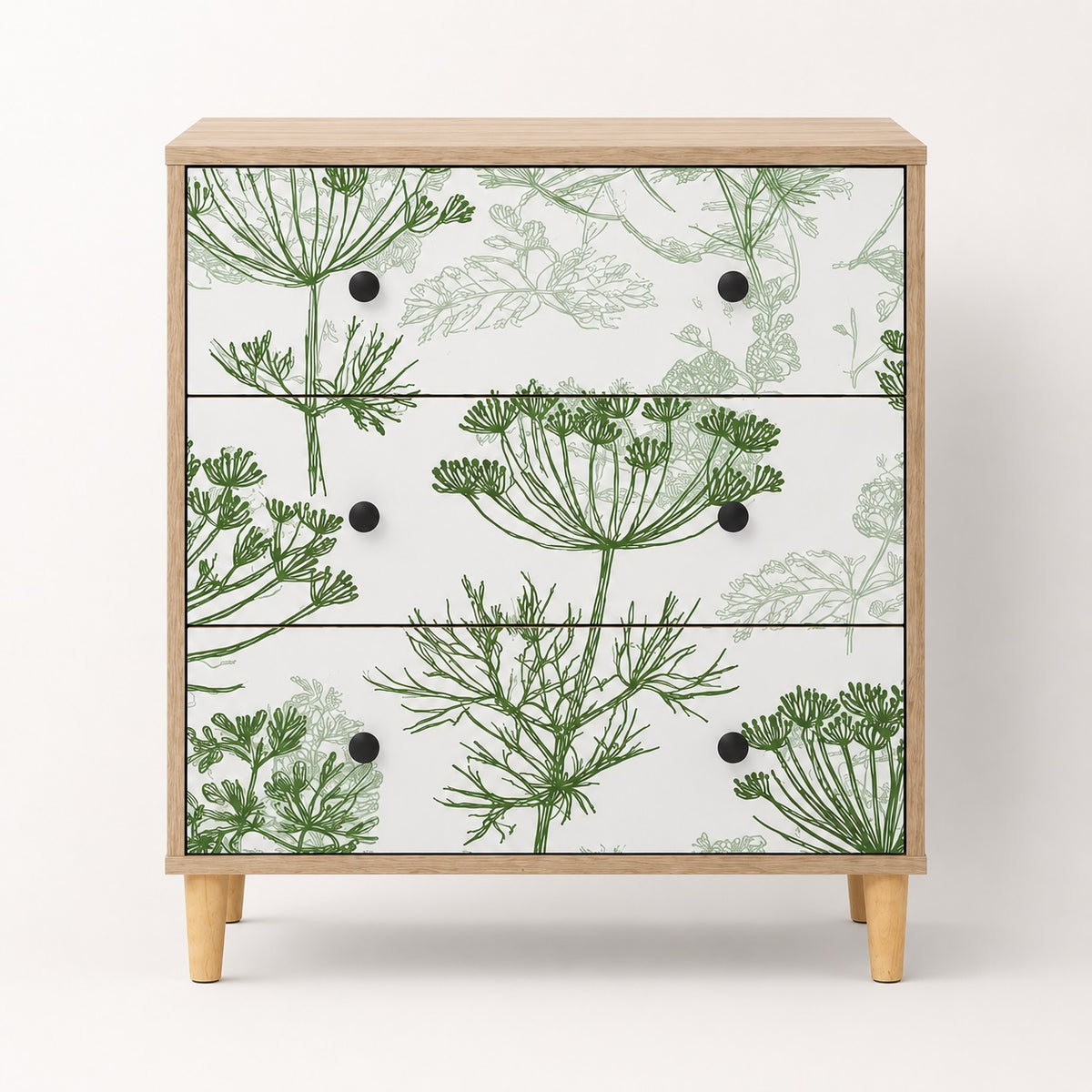 Commode design Dalia vue de face avec 3 tiroirs, motifs végétaux verts et pieds en bois clair.