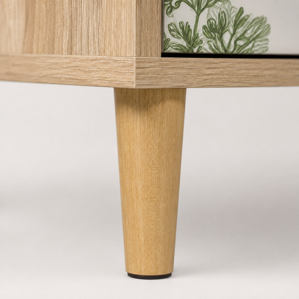 Détail du pied en bois clair de la commode 3 tiroirs Dalia au style naturel et élégant.