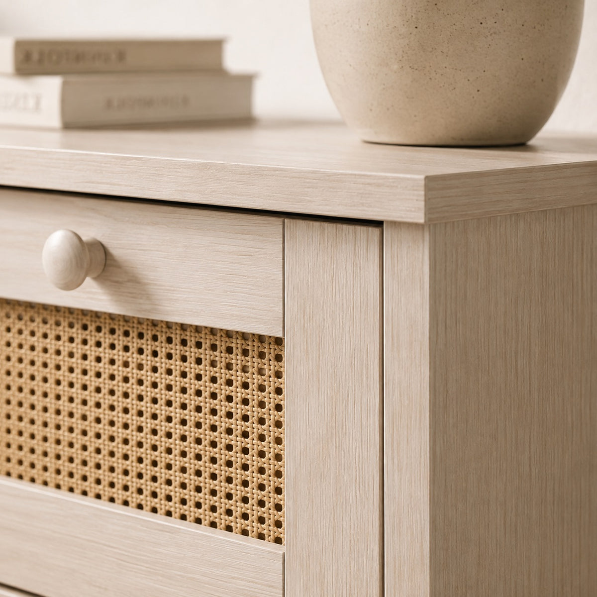 Détail de commode en rotin avec façade cannée, finition bois blanc et poignée ronde assortie.