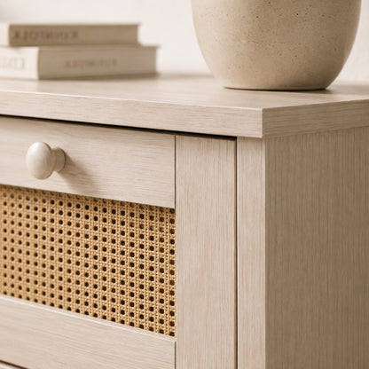 Détail de commode en rotin avec façade cannée, finition bois blanc et poignée ronde assortie.
