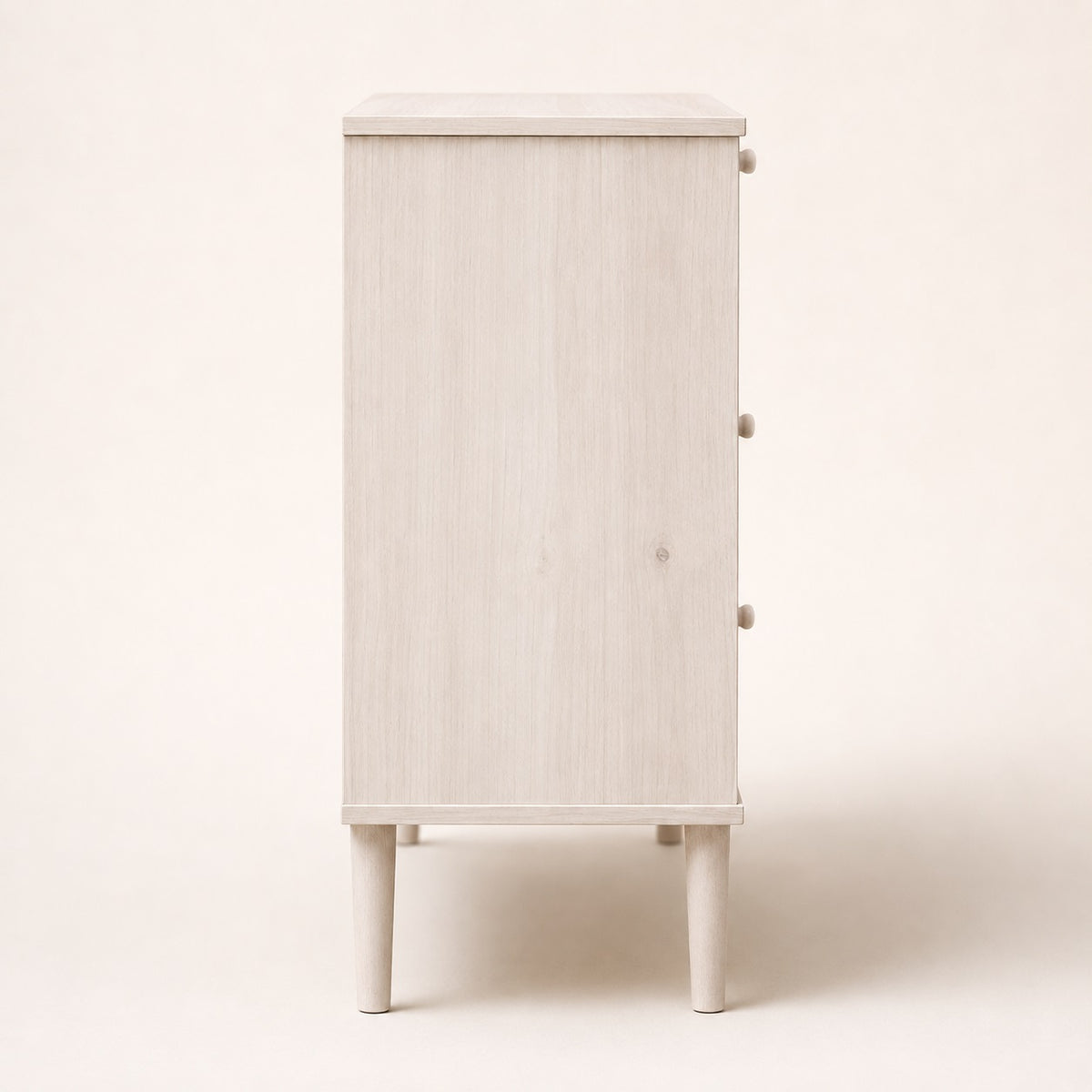 Vue de côté d’une commode 3 tiroirs blanche en rotin au design épuré et contemporain