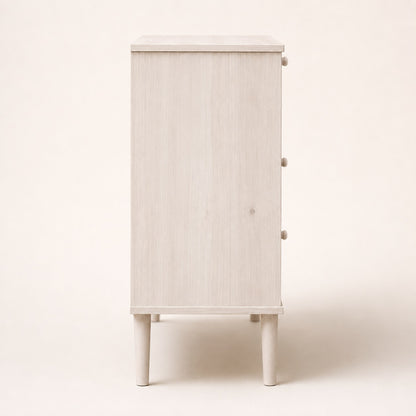 Vue de côté d’une commode 3 tiroirs blanche en rotin au design épuré et contemporain
