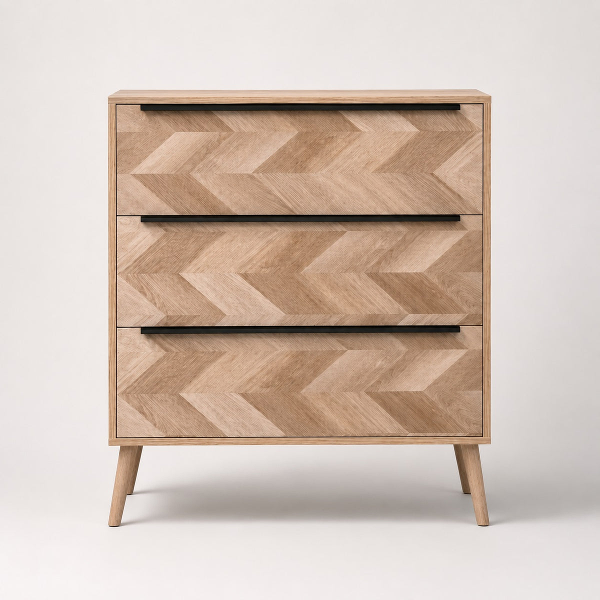 Commode 3 tiroirs design vue de face, en bois clair avec façades graphiques et poignées noires.