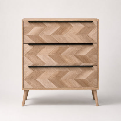 Commode 3 tiroirs design vue de face, en bois clair avec façades graphiques et poignées noires.