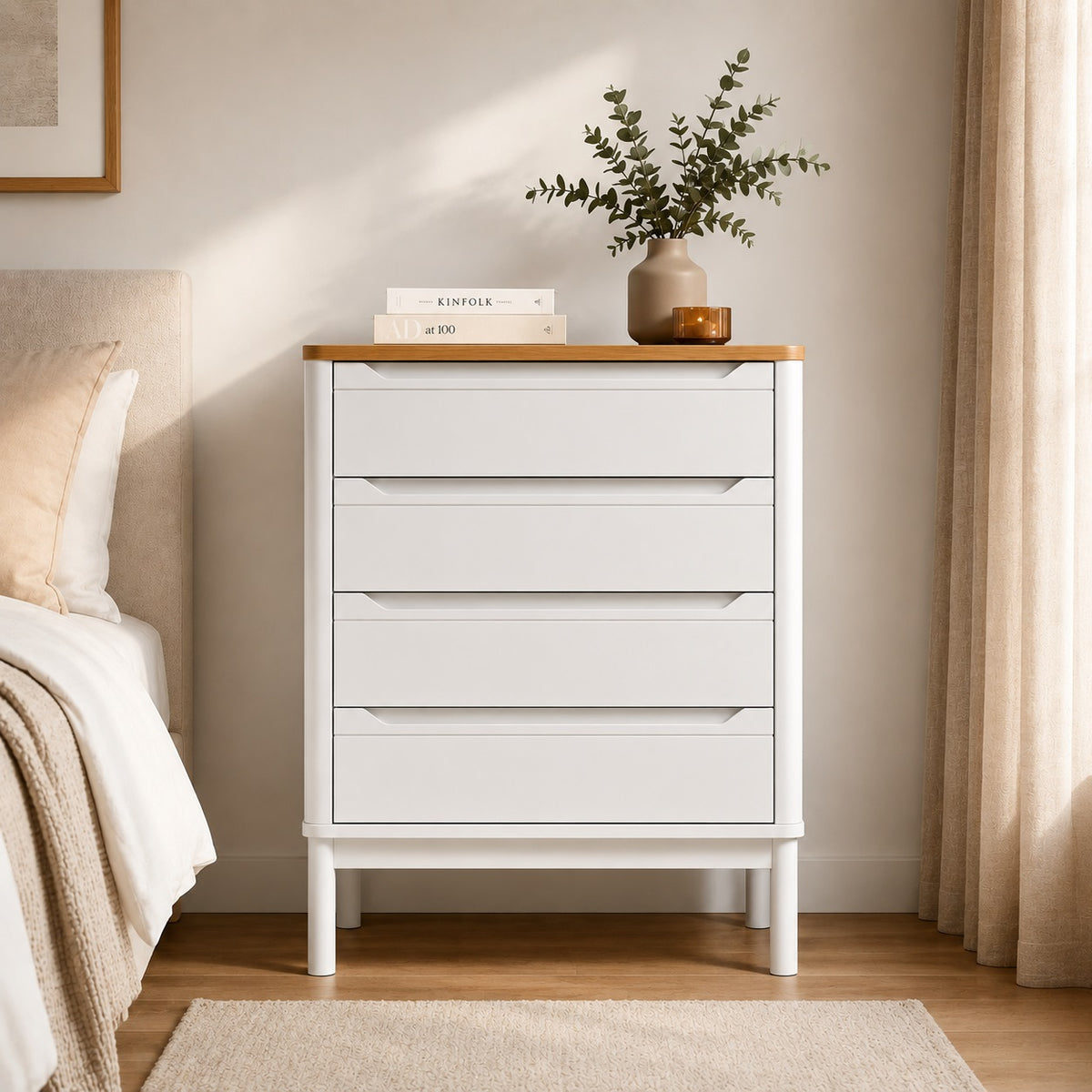 Commode 4 tiroirs blanche vue de face dans une chambre sobre aux tons beige et bois.