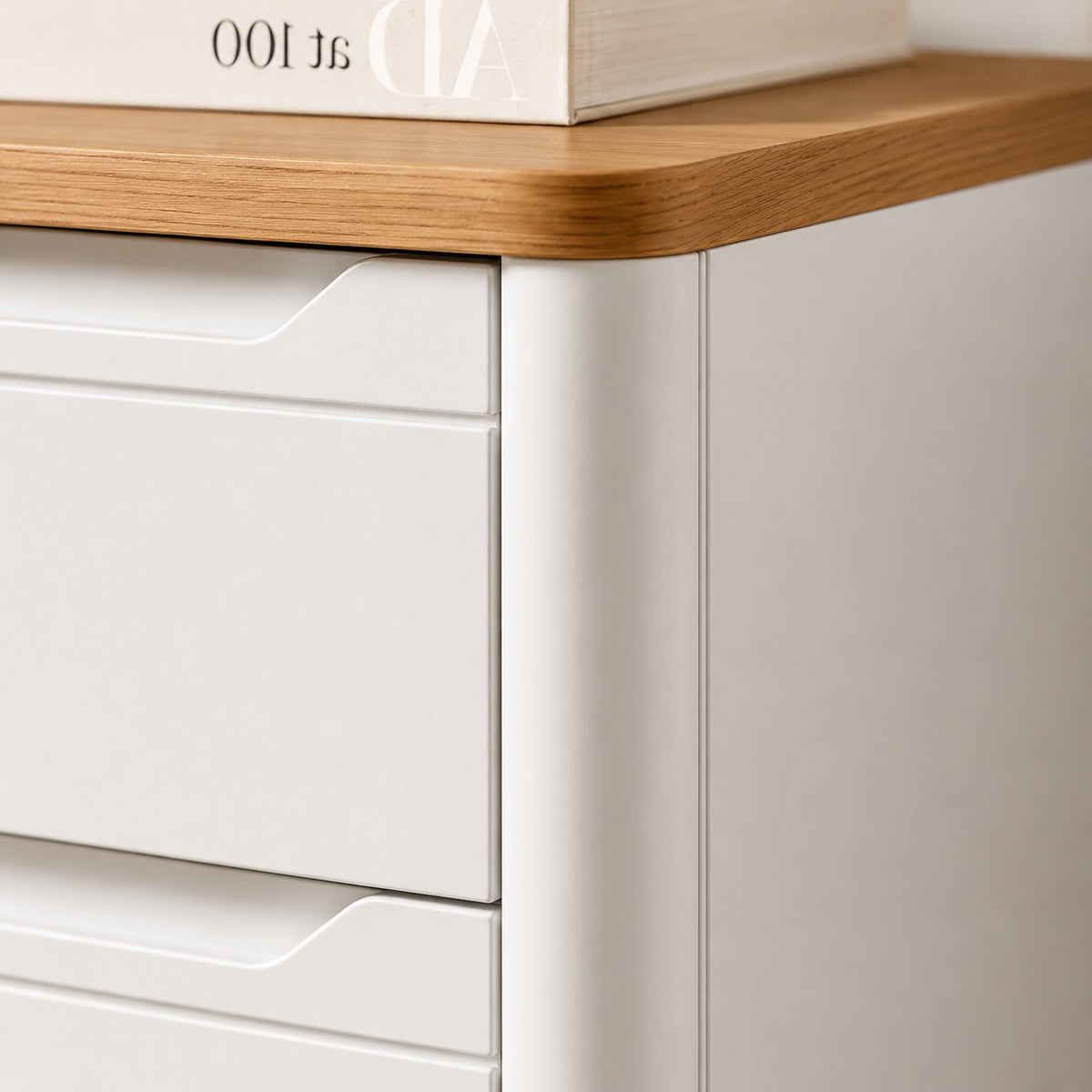 Détail de commode blanche 4 tiroirs avec plateau effet bois et finitions arrondies.