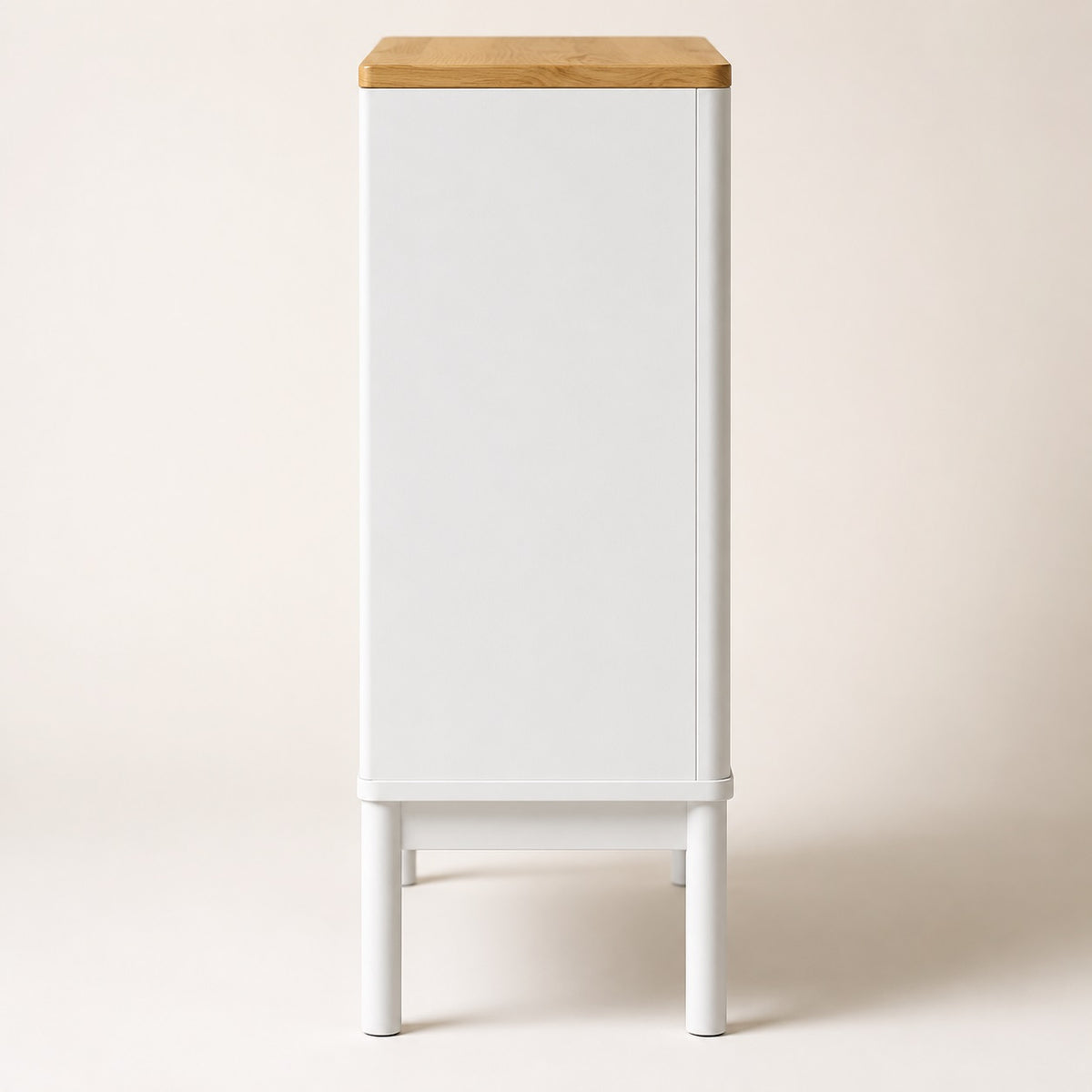 Vue de côté d’une commode blanche 4 tiroirs avec plateau effet bois et pieds surélevés.