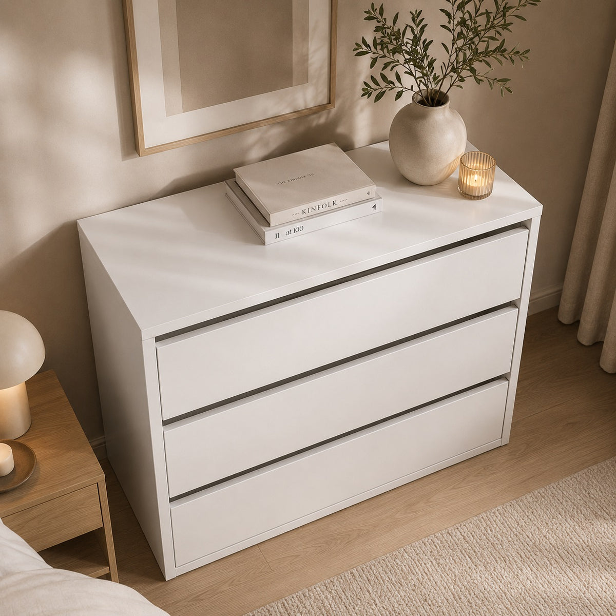 Commode blanche 3 tiroirs avec plateau spacieux et décoration sobre dans une chambre.