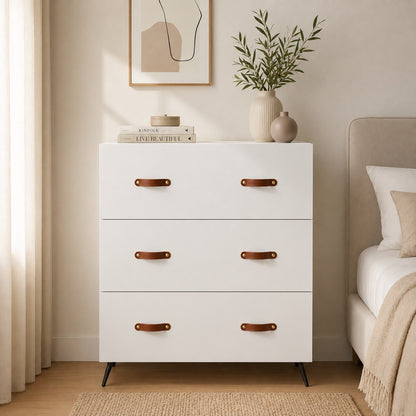 Commode 6 tiroirs blanche dans une chambre élégante, avec poignées effet cuir marron et pieds noirs.