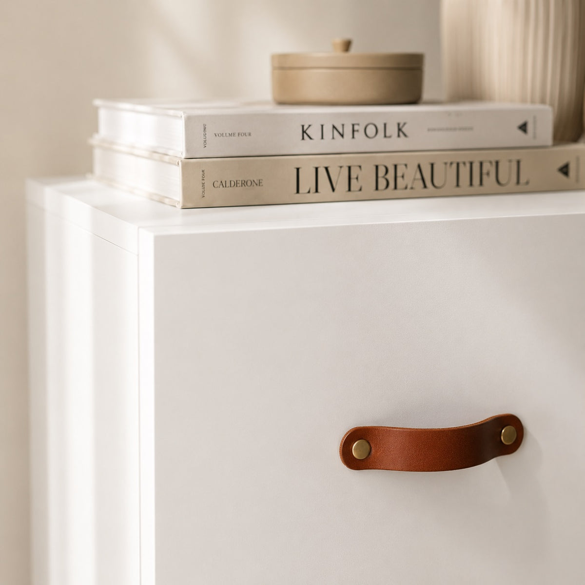 Détail de la commode blanche 6 tiroirs avec façade épurée et poignée effet cuir marron élégante.