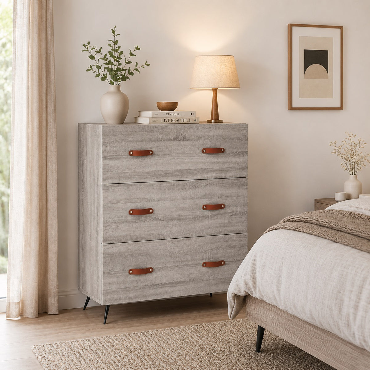 Commode 3 tiroirs grise Sylva vue de face, avec poignées effet cuir et piètement noir au design moderne.